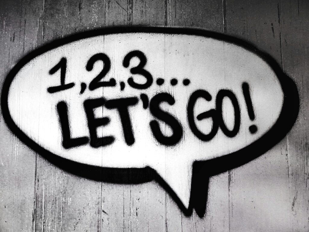 Black and white street art featuring a bold motivational message in a speech bubble. Motivational graphic with the words '1, 2, 3… Let’s Go!' encouraging beginners to take action in affiliate marketing.