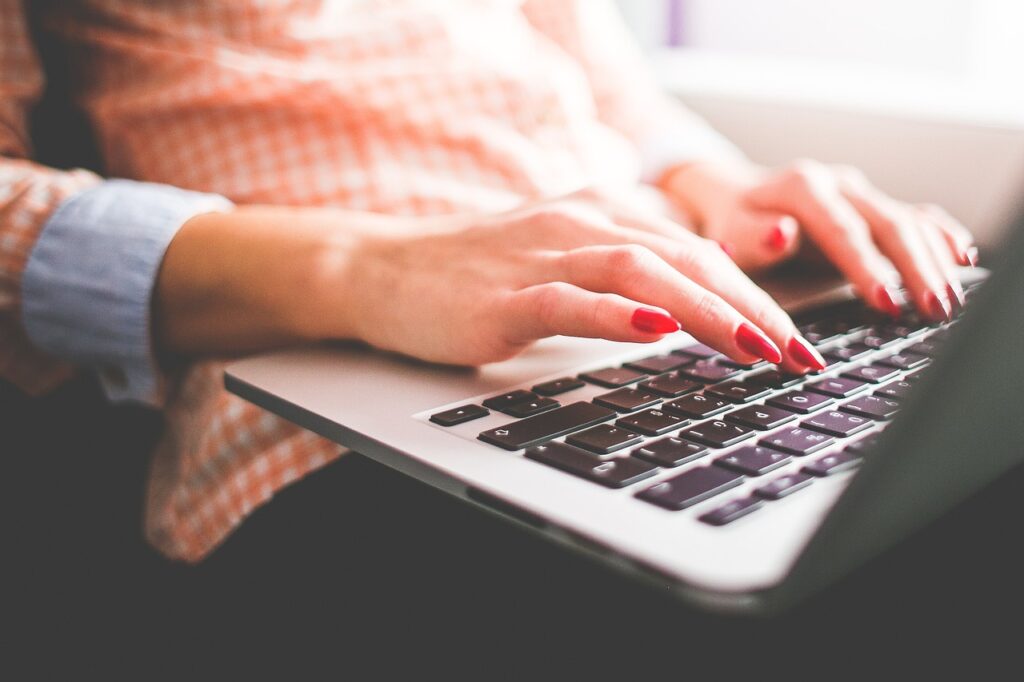 woman, typing, writing, macbook, notebook, computer, female, nails, girl, hands, lady, she, beautiful, red nails, typing, typing, typing, writing, writing, writing, writing, writing, nails. Woman using laptop to boost website traffic with Hungry for Hits digital marketing tool