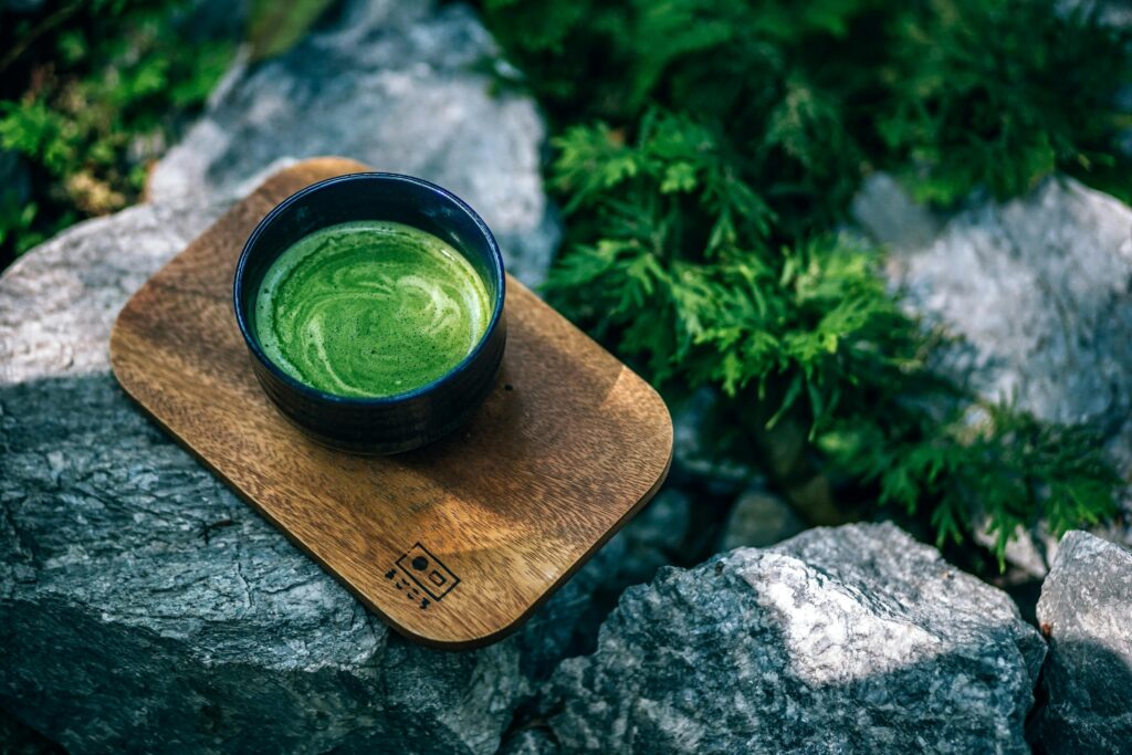 Top view of a green matcha tea served on a wooden tray outdoors, surrounded by rocks. A cup of matcha symbolizing The Matcha Moment with Affiliate Marketing.