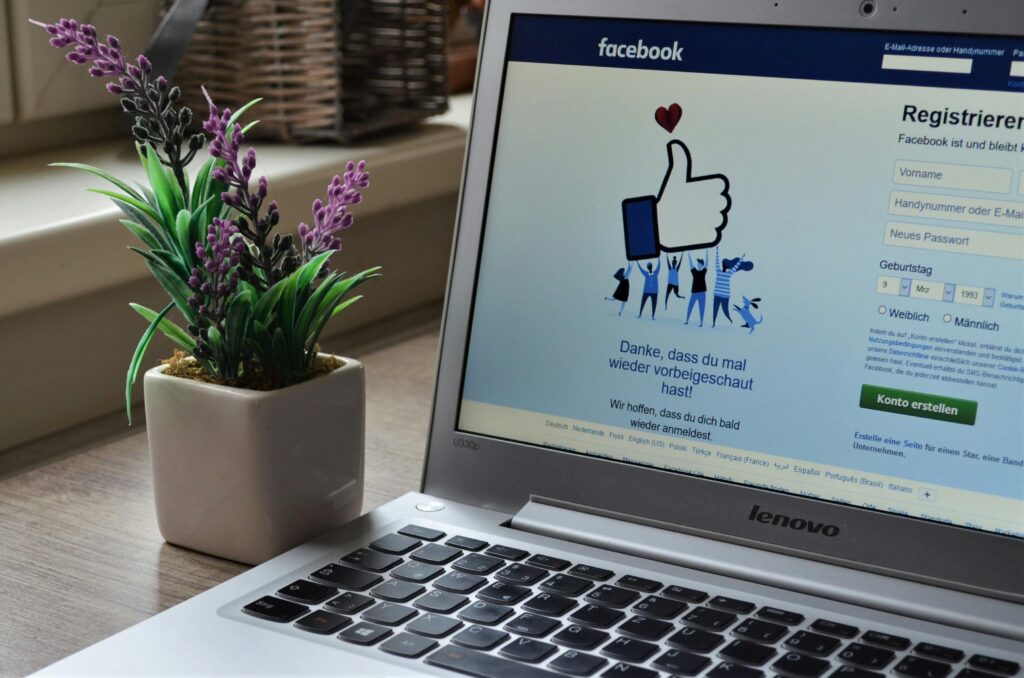 A Lenovo laptop displaying Facebook login beside a lavender plant indoors. Facebook interface open on a laptop screen, representing business management with Meta Business Suite.